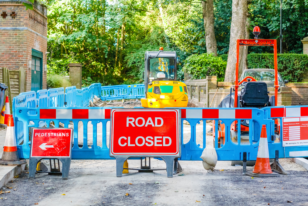 Road works being carried out in a section off area with a large road closed sign warning vehicles and pedestrians.