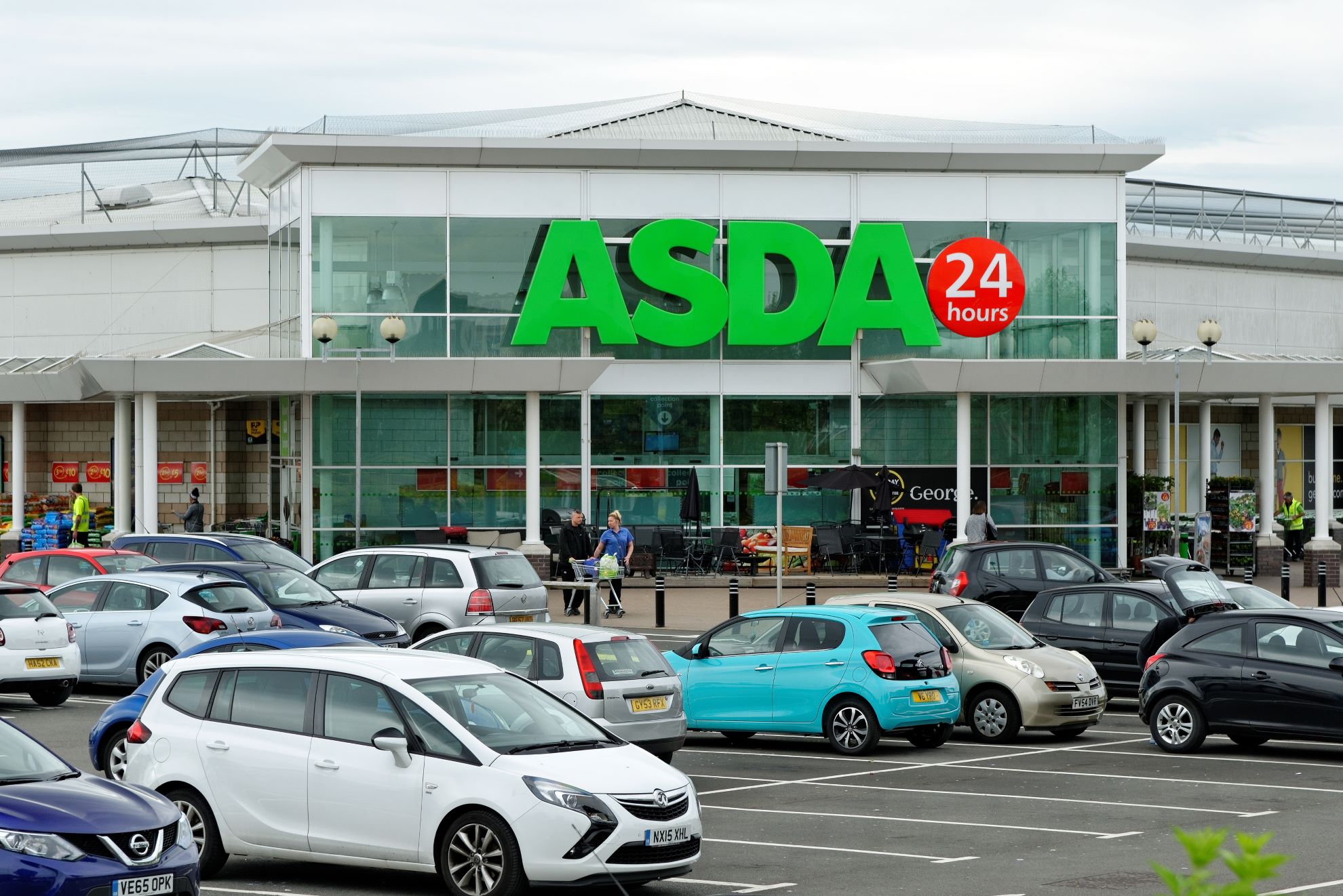 The shop front of an ASDA supermarket with lots of customers and cars outside.