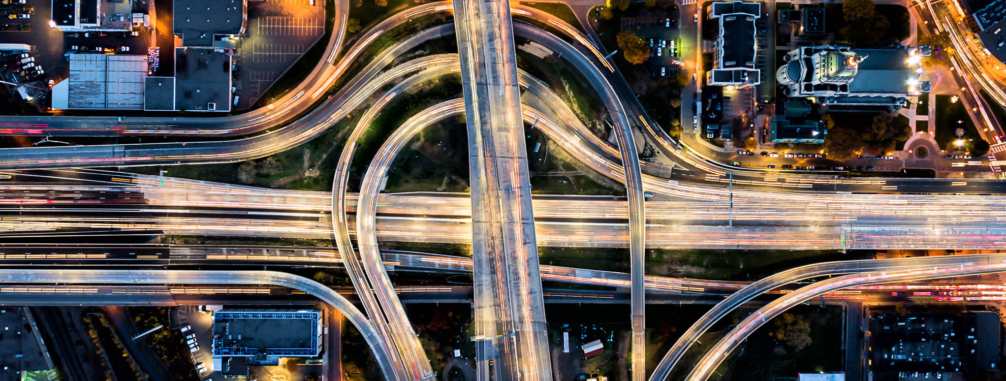 Aerial view of a complex road system going over a motorway, including lots of curving overpasses.