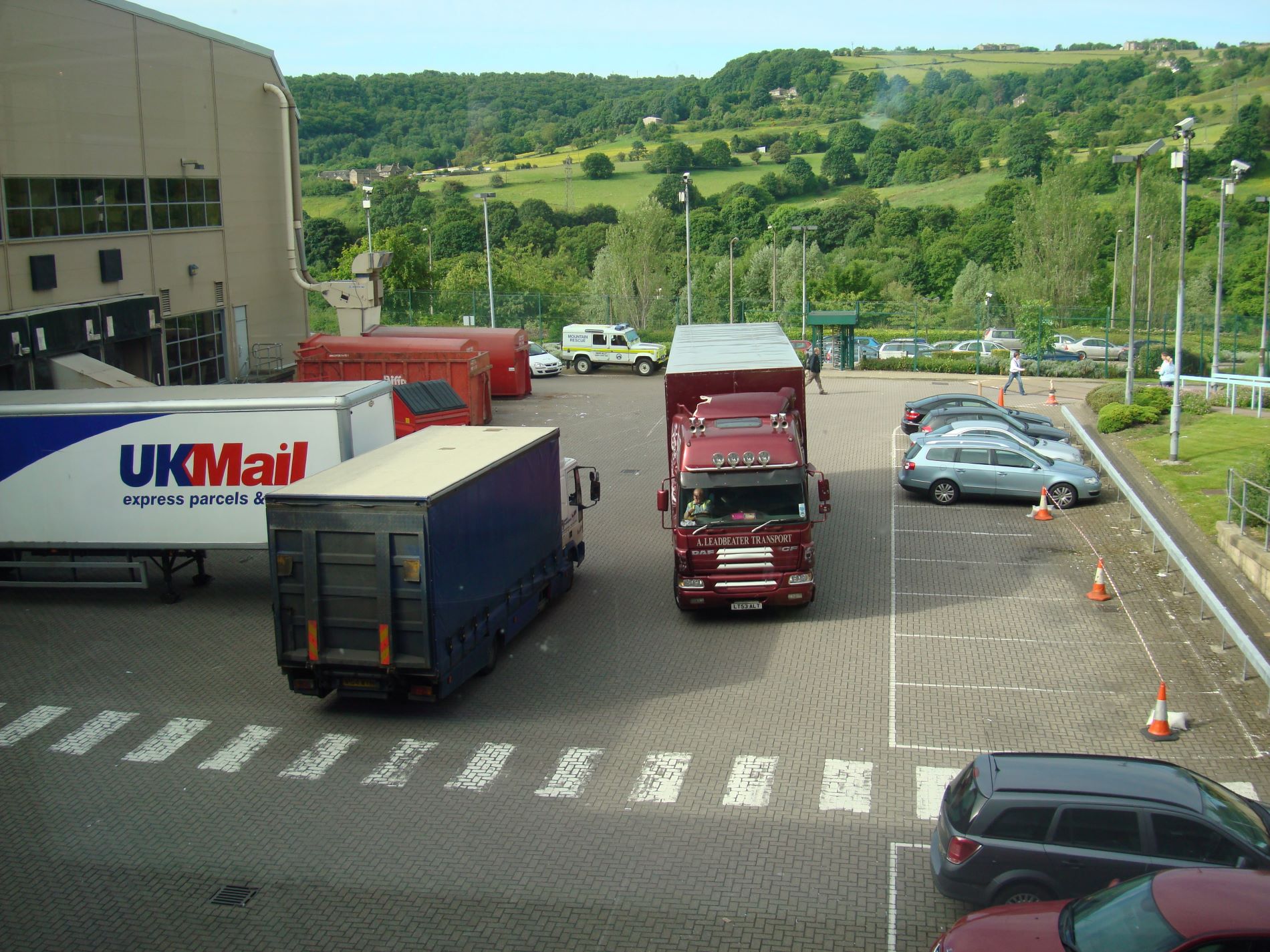 Several lorries delivering to the back of a large store.
