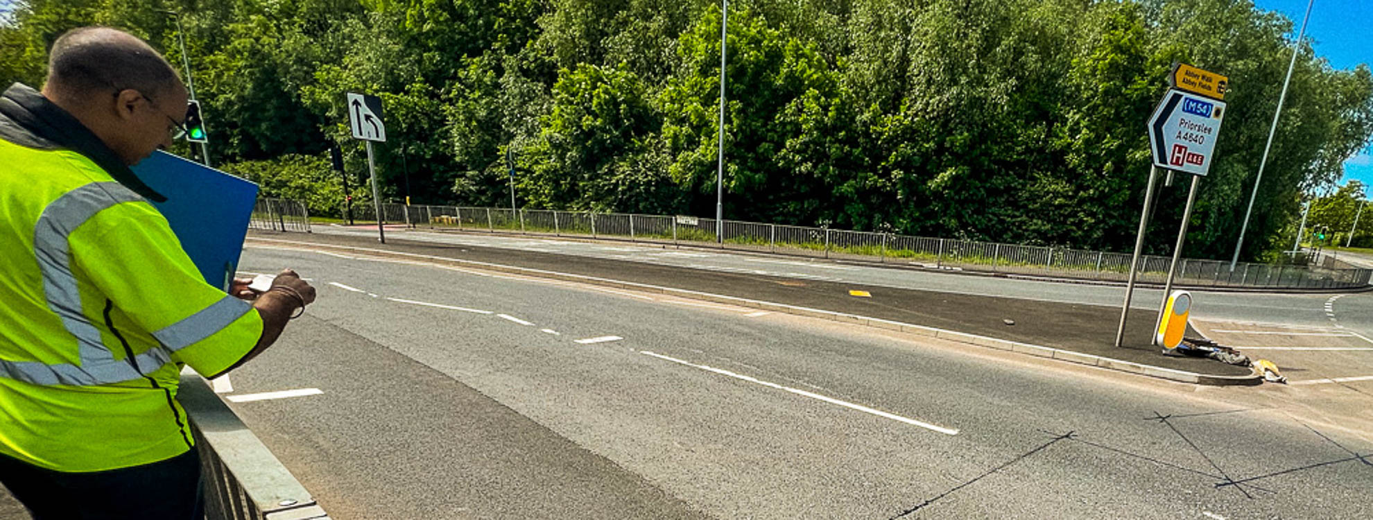 Man in a high vis jacket conducting a road safety audit on a main road.