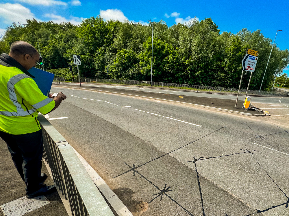 Man in a high vis jacket conducting a road safety audit on a main road.