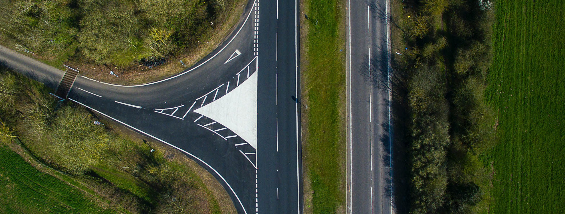 Aerial view of a junction next to a field and forest.