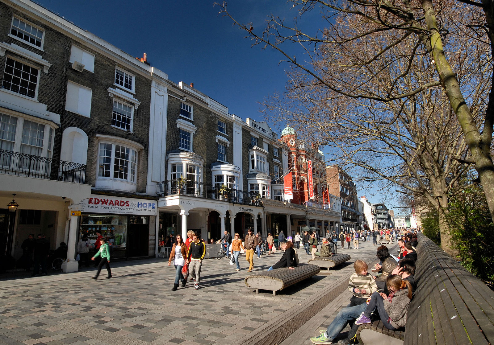 Large amount of people walking down a busy high street.