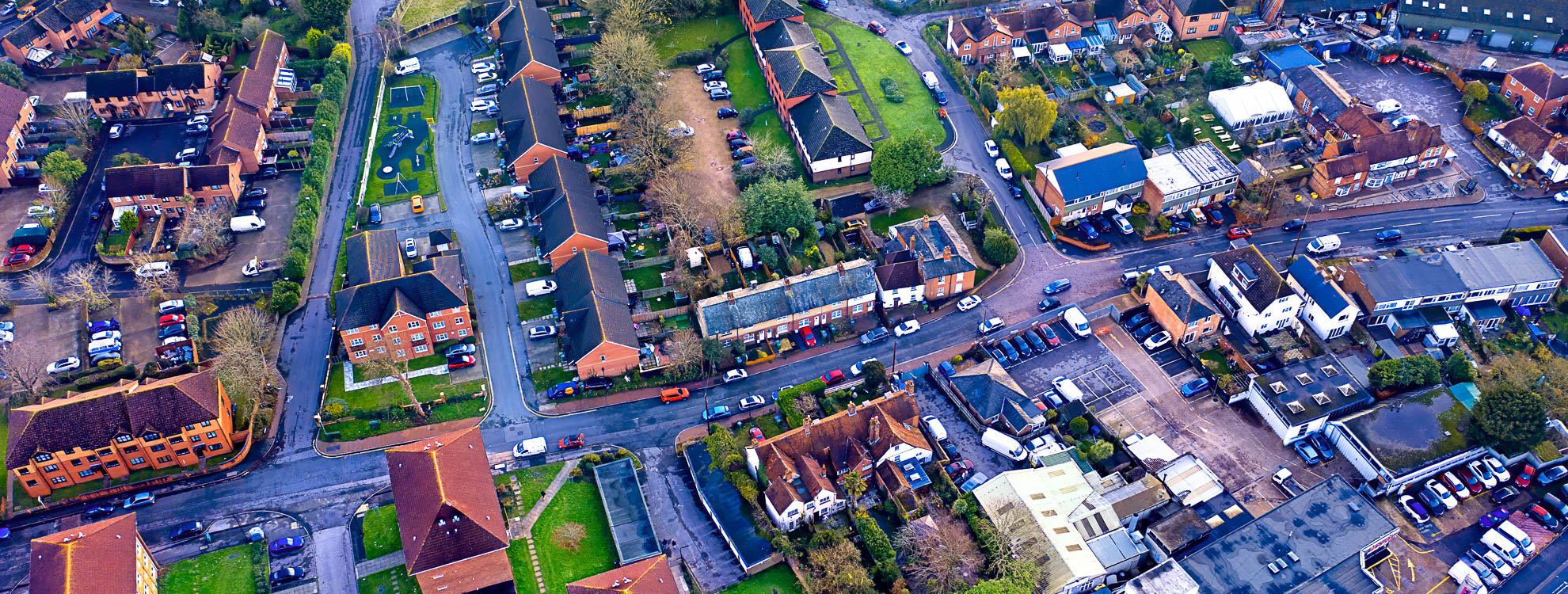 Aerial view of a busy housing estate, with a main road that runs through the middle of it.